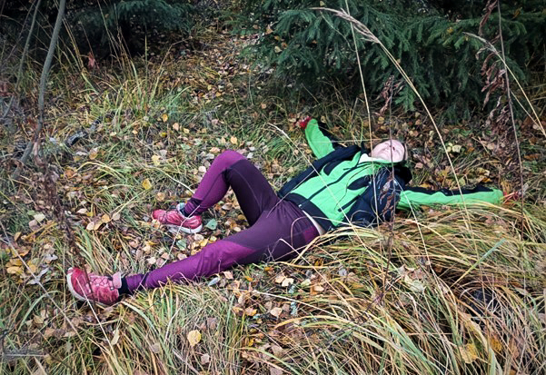 Henkilö makaamassa ruohikolla metsässä