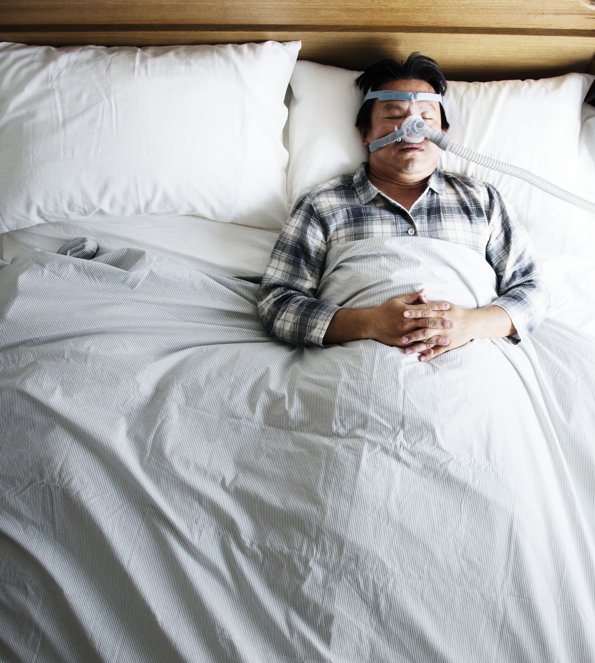 Mies nukkuu CPAP-laitteen kanssa