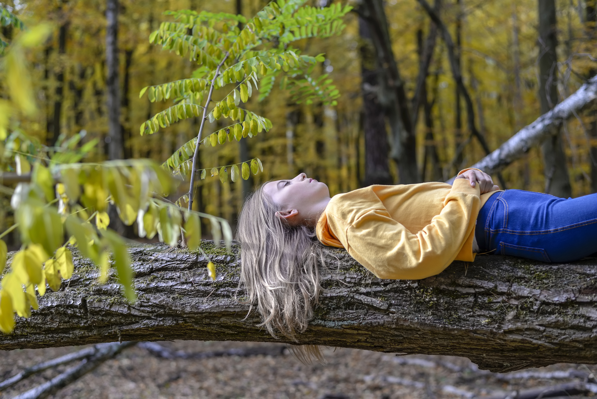 Nainen makaa metsässä tukin päällä rentoutuneena