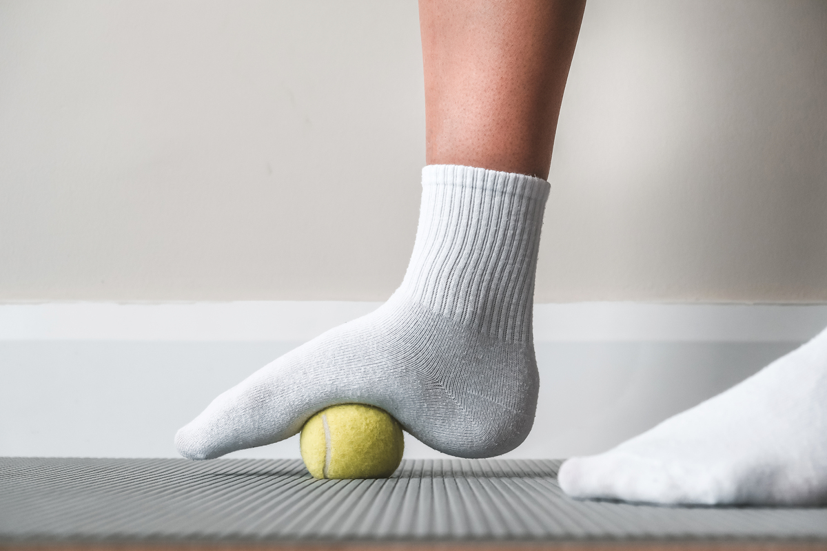 A person massaging their foot with a tennis ball