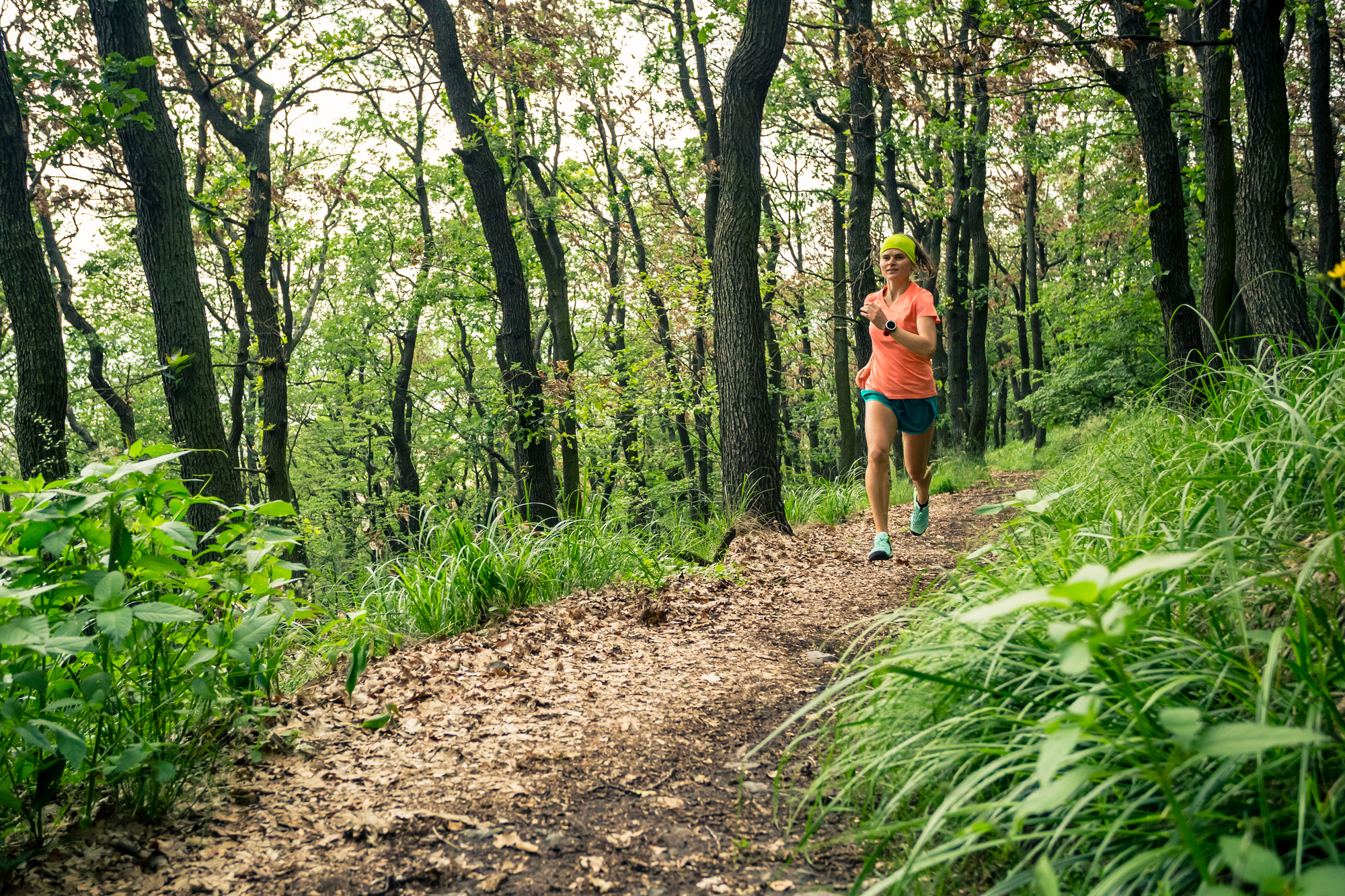 A woman running on a trail in a forest