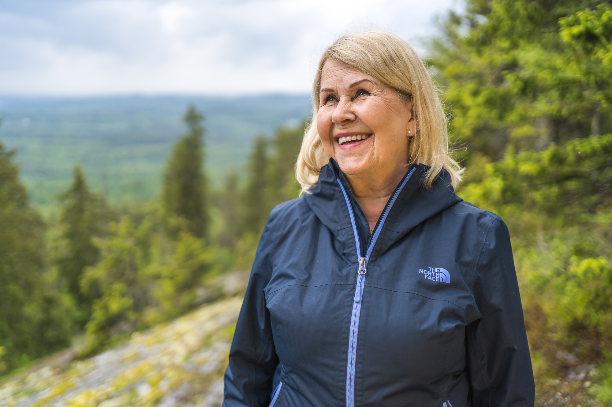A smiling person with a beautiful Finnish view over forest