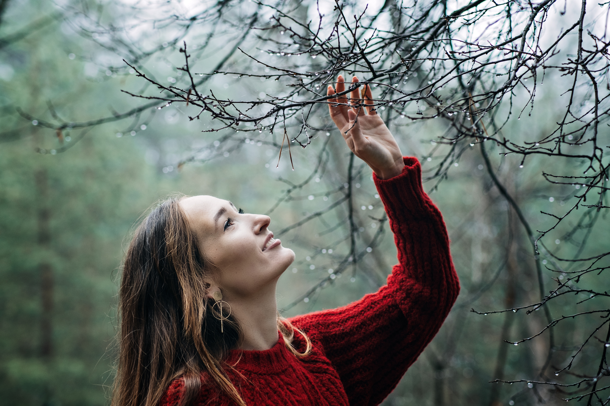 A woman admiring a tree with water drops